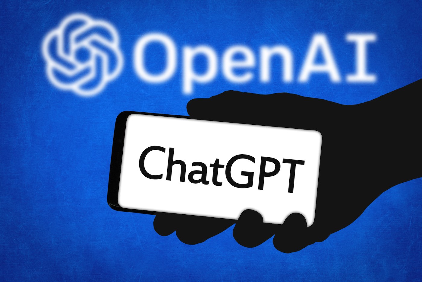 Ilustrasi ini menampilkan logo ChatGPT pada ponsel di depan logo OpenAI.